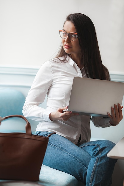 Attraente giovane donna con laptop Donna in caffetteria con gadget Donna di affari al chiuso