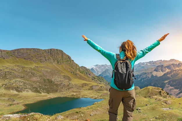 Attraente giovane donna con le braccia aperte che si gode la vita nel mezzo di una montagna con un lago in uno splendido paesaggio