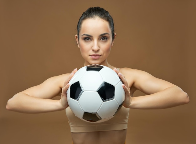 Attraente giovane donna con pallone da calcio in posa in studio