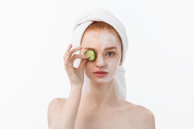 Attraente giovane donna con una bella pelle pulita. Maschera bianca e cetrioli. Trattamenti di bellezza e terapia termale cosmetologica.