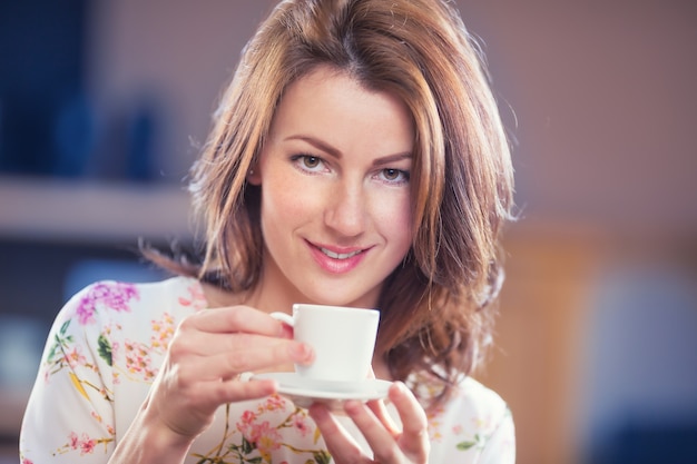 Attraente giovane donna con una tazza di caffè o tè.