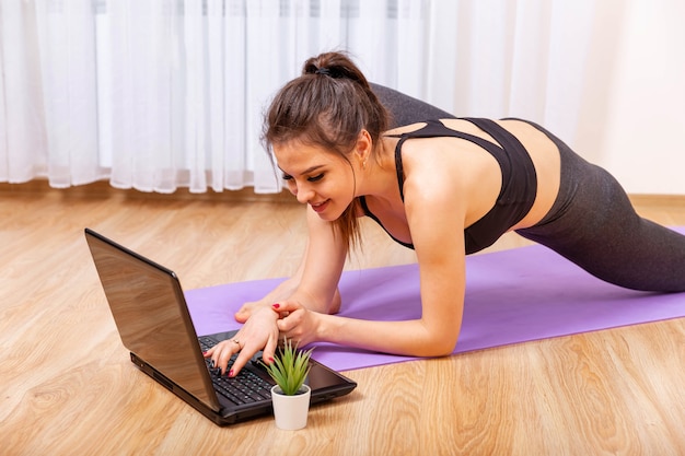 Attraente giovane donna facendo yoga e stretching online a casa