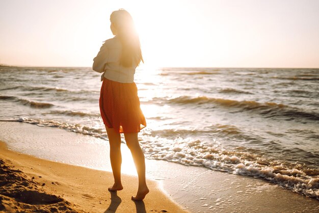 Attraente giovane donna felice in maglietta bianca capelli volanti godendo il suo tempo libero al tramonto all'aperto