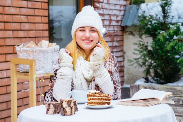 Attraente giovane donna felice seduta e mangiare il dessert al caffè