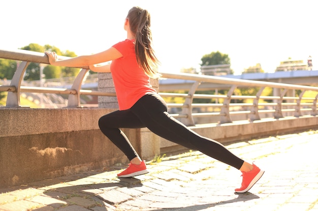 Attraente giovane donna fitness che indossa abbigliamento sportivo che si esercita all'aperto, esercizi di stretching.