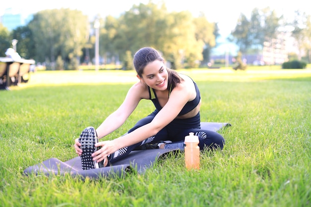 Attraente giovane donna fitness che si esercita all'aperto, esercizi di stretching.