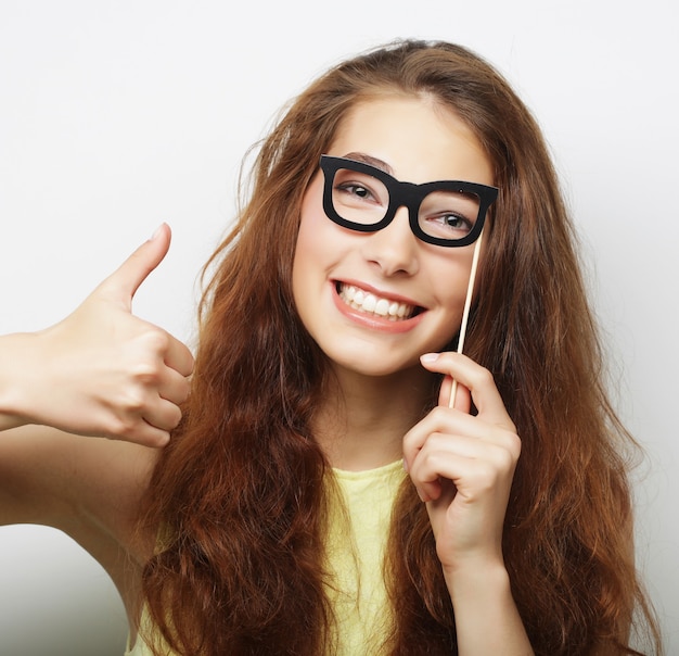 Attraente giovane donna giocosa con occhiali finti, pronta per la festa