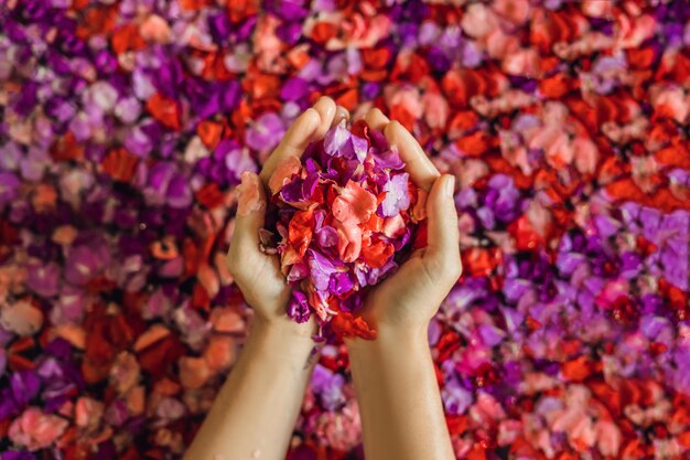 Attraente giovane donna in bagno con petali di fiori tropicali e oli aromatici. Trattamenti termali per il ringiovanimento della pelle. Donna seducente nel salone della stazione termale. Ragazza rilassante nella vasca idromassaggio con petali di fiori. Lusso sp