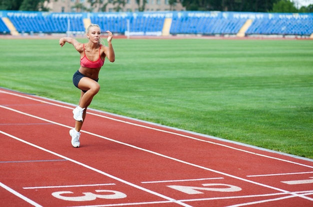 Attraente giovane donna in una tuta sportiva che corre verso il traguardo