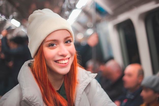 Attraente giovane donna rossa che guarda alla telecamera con un caldo sorriso in un veicolo di trasporto pubblico