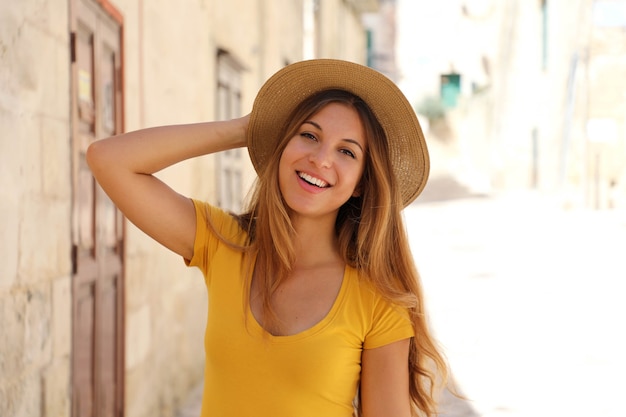 Attraente giovane donna turistica sorridente con cappello di paglia in una giornata di sole d'estate in vacanza