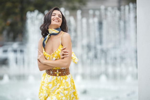 Attraente giovane donna vicino alla fontana. Bella femmina all'aperto. Signora nel ritratto del vestito giallo.