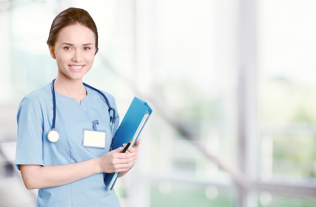 Attraente giovane dottoressa con interni sfocati dell'ospedale sullo sfondo