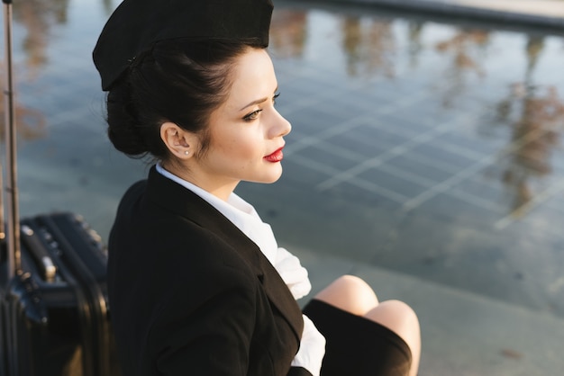 Attraente giovane hostess in uniforme in attesa del suo volo, guardando il cielo