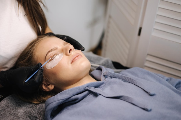 Attraente modello di capelli biondi in uno studio di bellezza con procedura utile moderna per la laminazione delle ciglia per