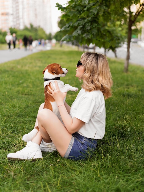 Attraente ragazza abbraccia e bacia il suo cucciolo di cane Jack Russell Terrier nel parco