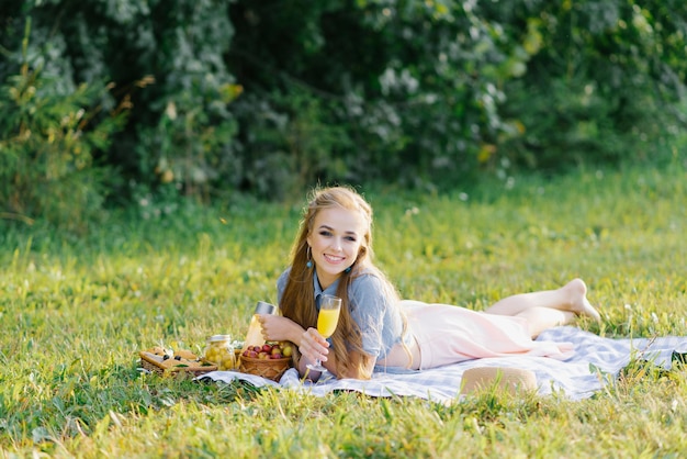 Attraente ragazza allegra sdraiata su una coperta e trascorrere il fine settimana rilassandosi nel parco all'aperto