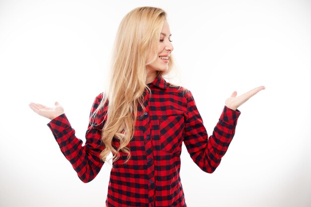 Attraente ragazza bionda promotore che tiene qualcosa in mano dimostrando lo spazio vuoto con la faccia eccitata isolata su sfondo bianco