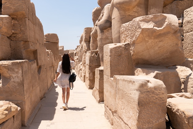 Attraente ragazza bruna in abito bianco cammina tra le antiche rovine del tempio di Karnak a Luxor. Egitto