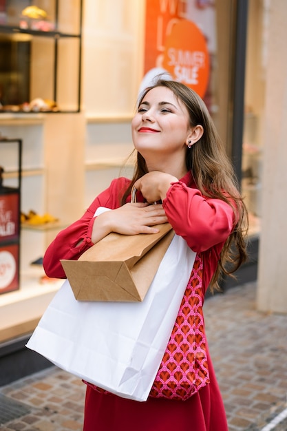 Attraente ragazza in abito rosa brillante, felice di acquistare nuovi vestiti alla moda durante il periodo di alta vendita