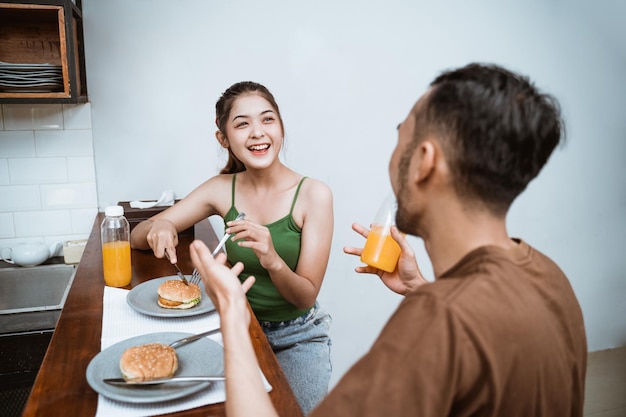 Attraente ragazza in chat con il giovane a colazione al tavolo della sala da pranzo