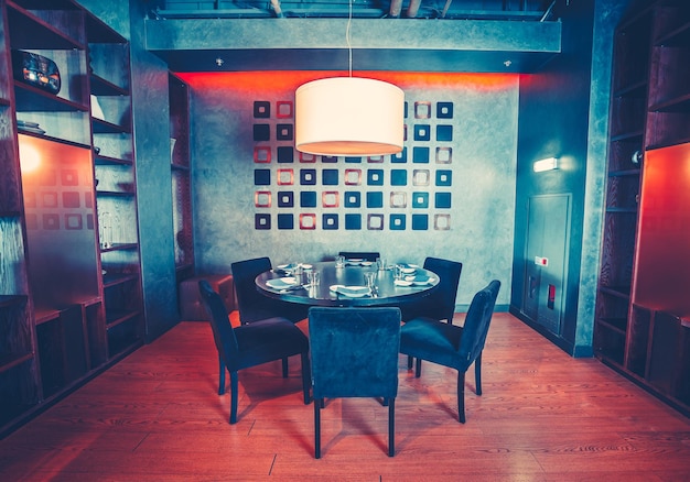 Attraente ristorante all'interno della sala principale con l'accogliente tavolo rotondo e sedie di velluto designer