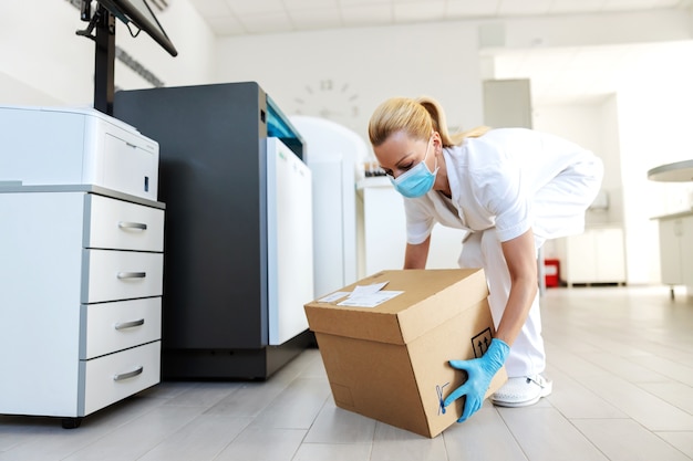 Attraente scatola da trasporto per assistente di laboratorio bionda positiva con vaccini per Covid 19.