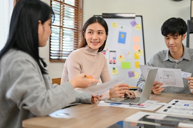 Attraente stilista asiatica che discute con il suo collega nel concetto di design UI UX della riunione