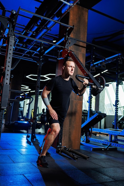 Attraente uomo adulto facendo esercizi e sollevamento pesi in palestra. Allenamento sportivo in palestra