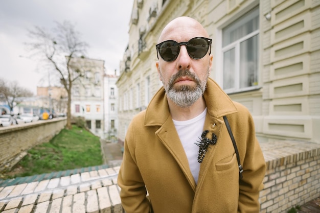 Attraente uomo alla moda con la barba in elegante cappotto marrone nella strada della città di Kiev