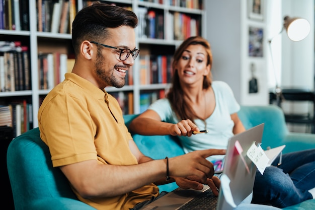 Attraenti giovani studenti uomo e donna seduti nella biblioteca universitaria e l'apprendimento.