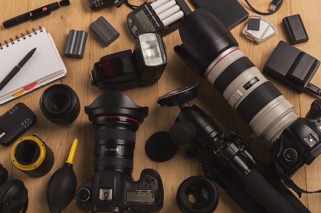 Attrezzatura fotografica. Vista dall'alto di diverse attrezzature personali per fotografo o designer creativo su tavola di legno, copia spazio