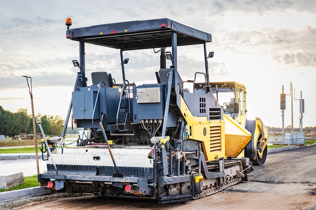 Attrezzature per pavimentazione in asfalto. Asfaltatrice e rullo vibrante pesante. Costruzione di nuove strade e svincoli stradali. Macchinari industriali per costruzioni pesanti.