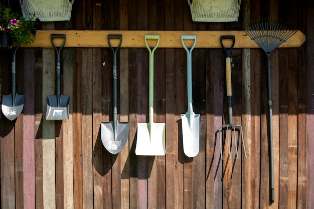 Attrezzi da giardinaggio appesi sulla parete di legno, strumenti.