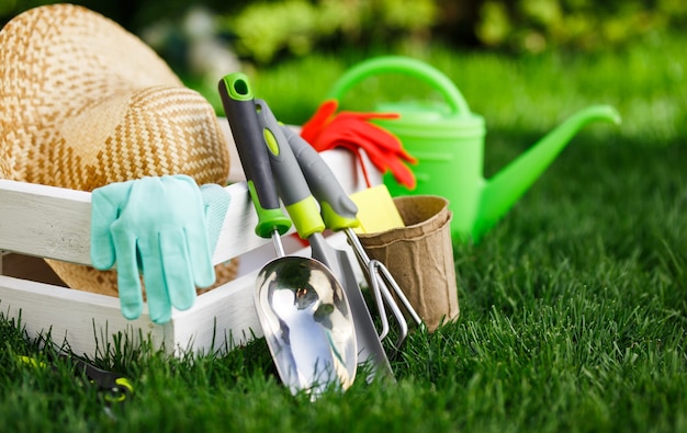 Attrezzi da giardinaggio e un cappello di paglia sull'erba del giardino.