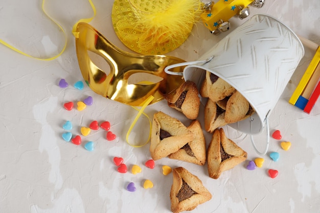 Attributi di carnevale e dolci ebraici tradizionali biscotti hamantaschen in un piatto su uno sfondo di legno