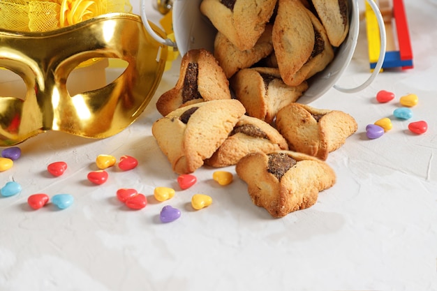 Attributi di carnevale e dolci ebraici tradizionali biscotti hamantaschen in un piatto su uno sfondo di legno