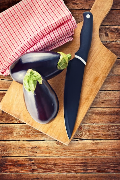 Aubergine o Aubergine con coltello su tavola da taglio in legno