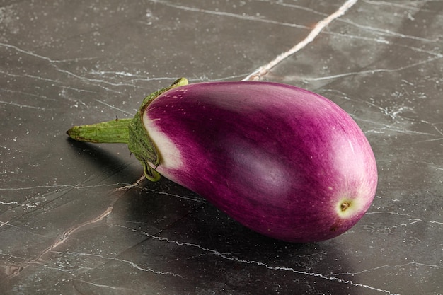 Aubergine purpuree crude mature per la cottura sullo sfondo