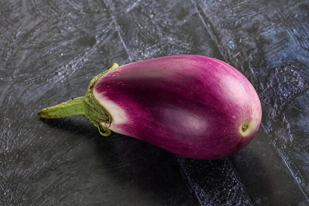 Aubergine purpuree crude mature per la cottura sullo sfondo