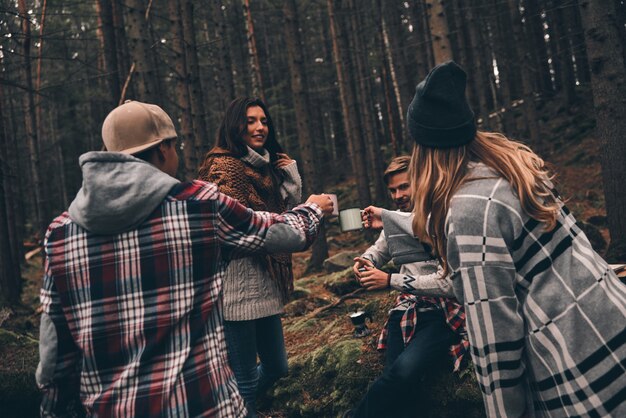 Auguri all'amicizia! Gruppo di giovani felici che trascorrono del tempo insieme durante le escursioni nei boschi wood