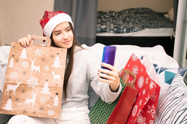 Auguri di Capodanno e Natale onlineUna ragazza con il cappello di Babbo Natale chiama la famiglia e gli amici tramite collegamento video