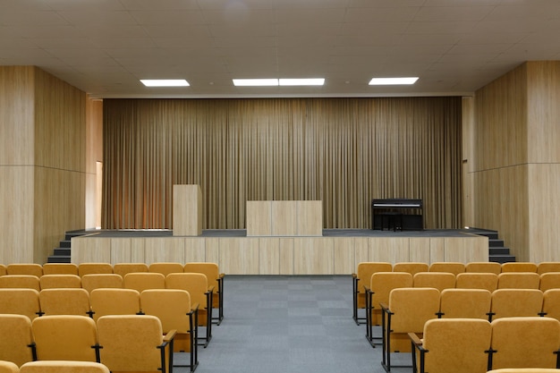 Aula magna della scuola con sedie e palco vuoti, sala riunioni interna per conferenze e conferenze. Sala per un piccolo pubblico per organizzare spettacoli o incontri di lavoro.