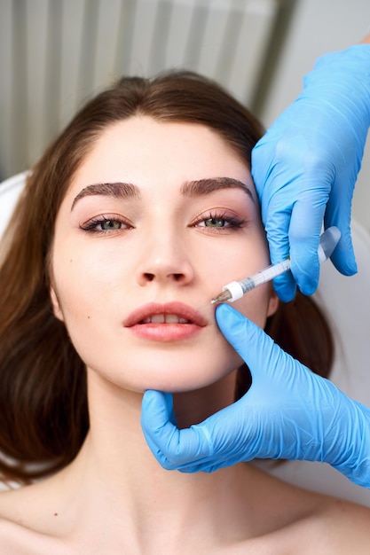 Aumento delle labbra Closeup di estetista medico mani che fanno la procedura di bellezza alle labbra femminili con siringa giovani donne bocca che ricevono iniezione di acido ialuronico cosmetologia trattamento mesoterapia