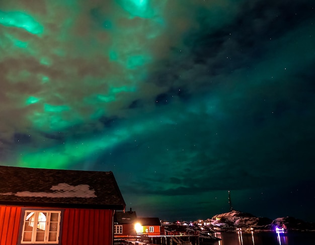 Aurora boreale con cielo nuvoloso sopra il villaggio di Tind nelle Isole Lofoten