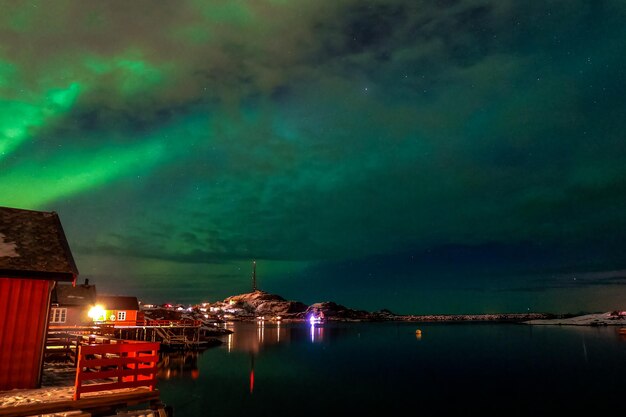 Aurora boreale con cielo nuvoloso sopra il villaggio di Tind nelle Isole Lofoten