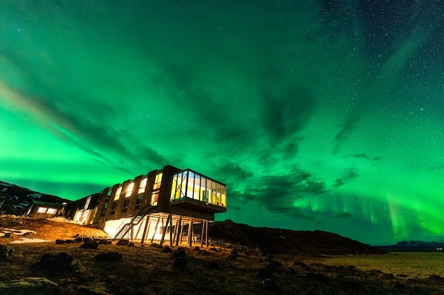 Aurora boreale Le luci del nord brillano sopra un hotel di lusso nel deserto vulcanico in inverno in Islanda