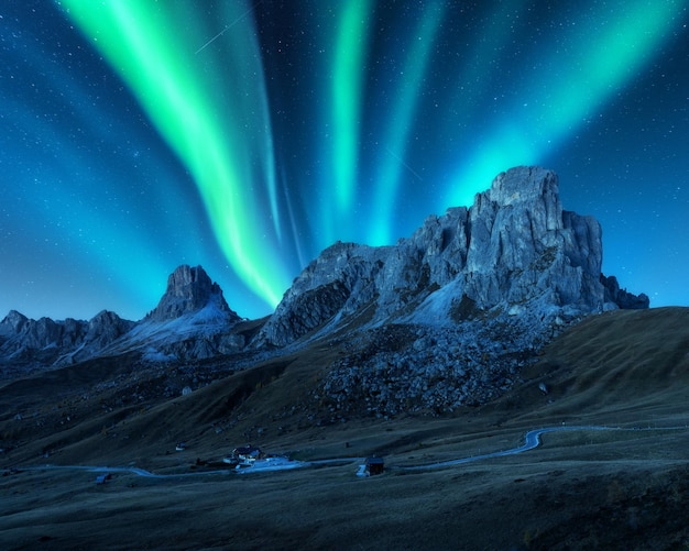Aurora boreale sopra le montagne di notte in Europa Aurora boreale Cielo stellato con luci polari e rocce alte Bellissimo paesaggio con edifici stradali aurora sulla cresta della montagna della collina Viaggio