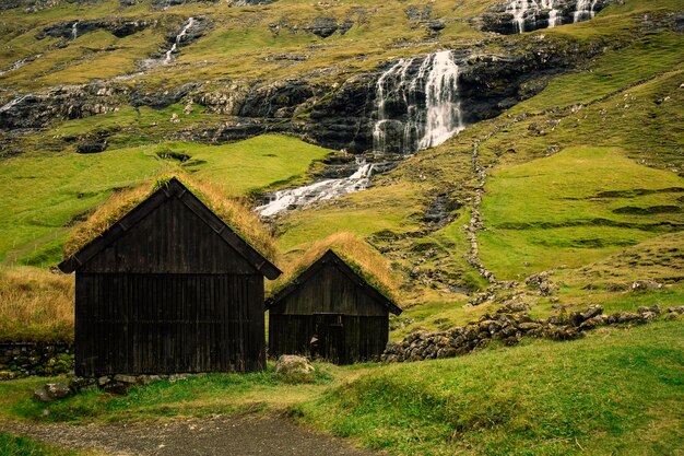 Autentiche case di legno con una cascata sullo sfondo nelle Isole Faroe