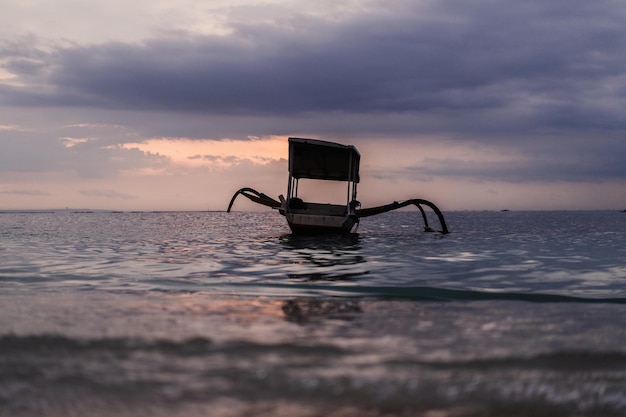 Autentico peschereccio balinese nell'acqua al tramonto. Sfondo.